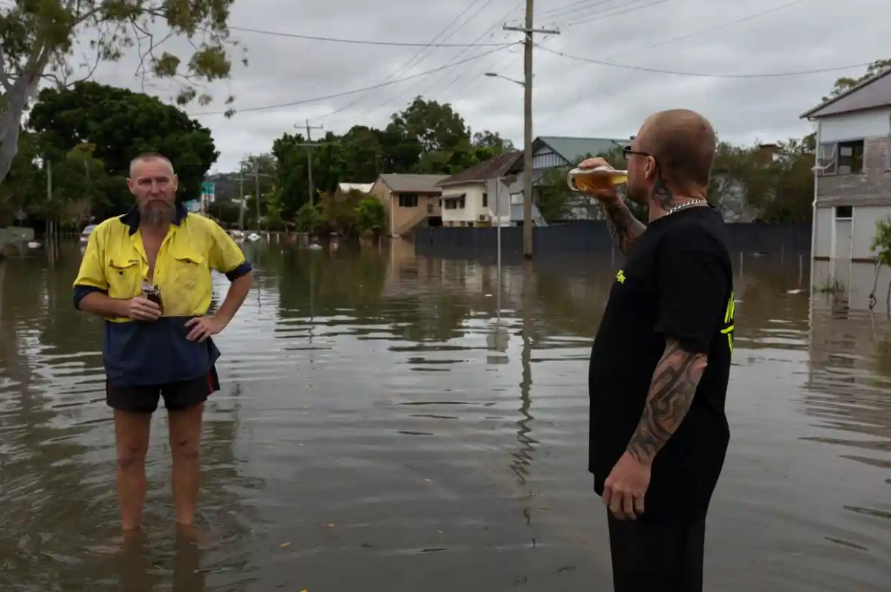 Những người hàng xóm Steve Miller và Matt Lewis đứng trong dòng nước lũ đang rút. Ảnh: The Guardian.