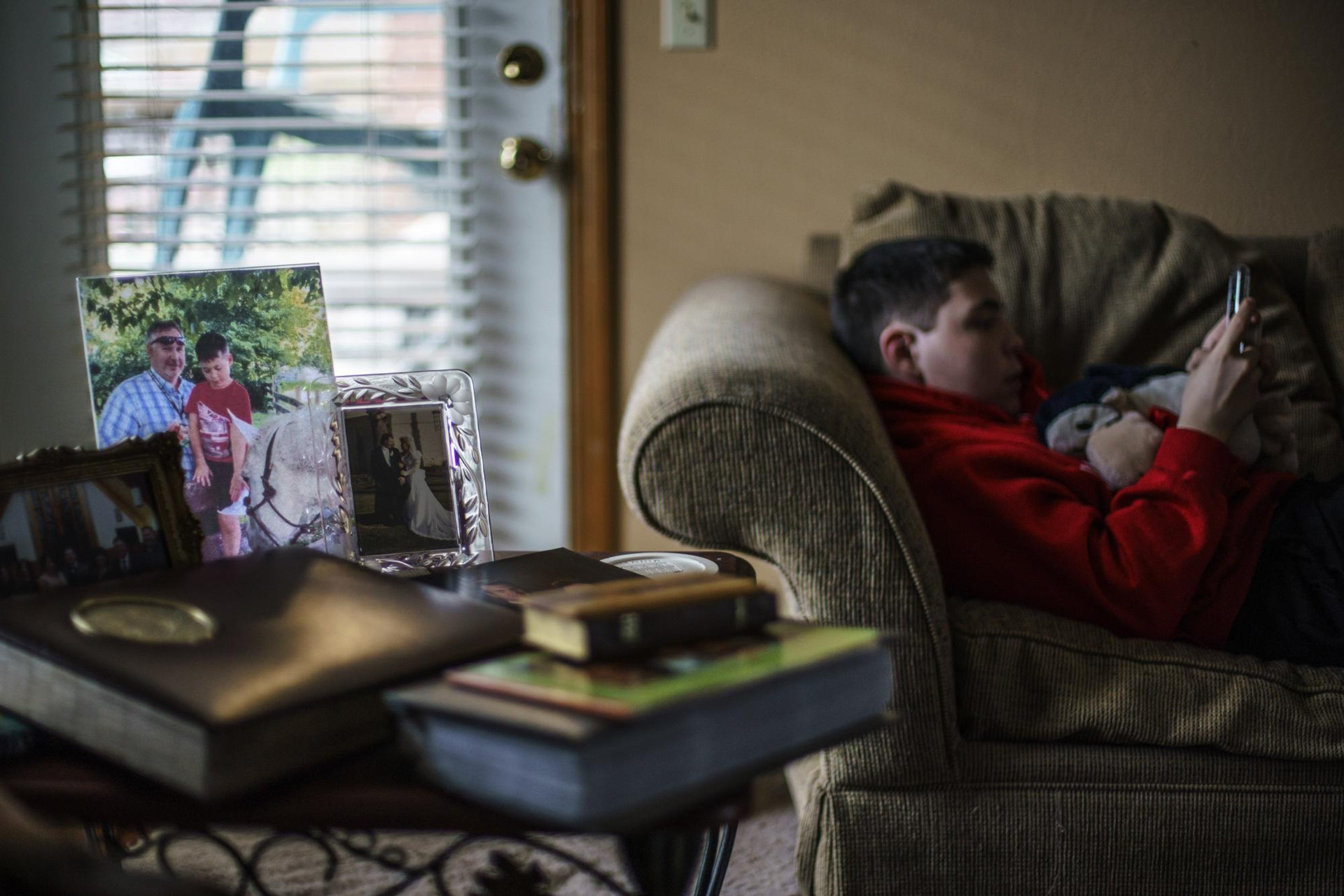 Landon Quackenbush, 13 tuổi, nằm trên chiếc ghế dài bên cạnh bức ảnh của anh và cha anh, Larry Quackenbush, tại nhà của họ ở Springfield, Mo. Ảnh: AP.