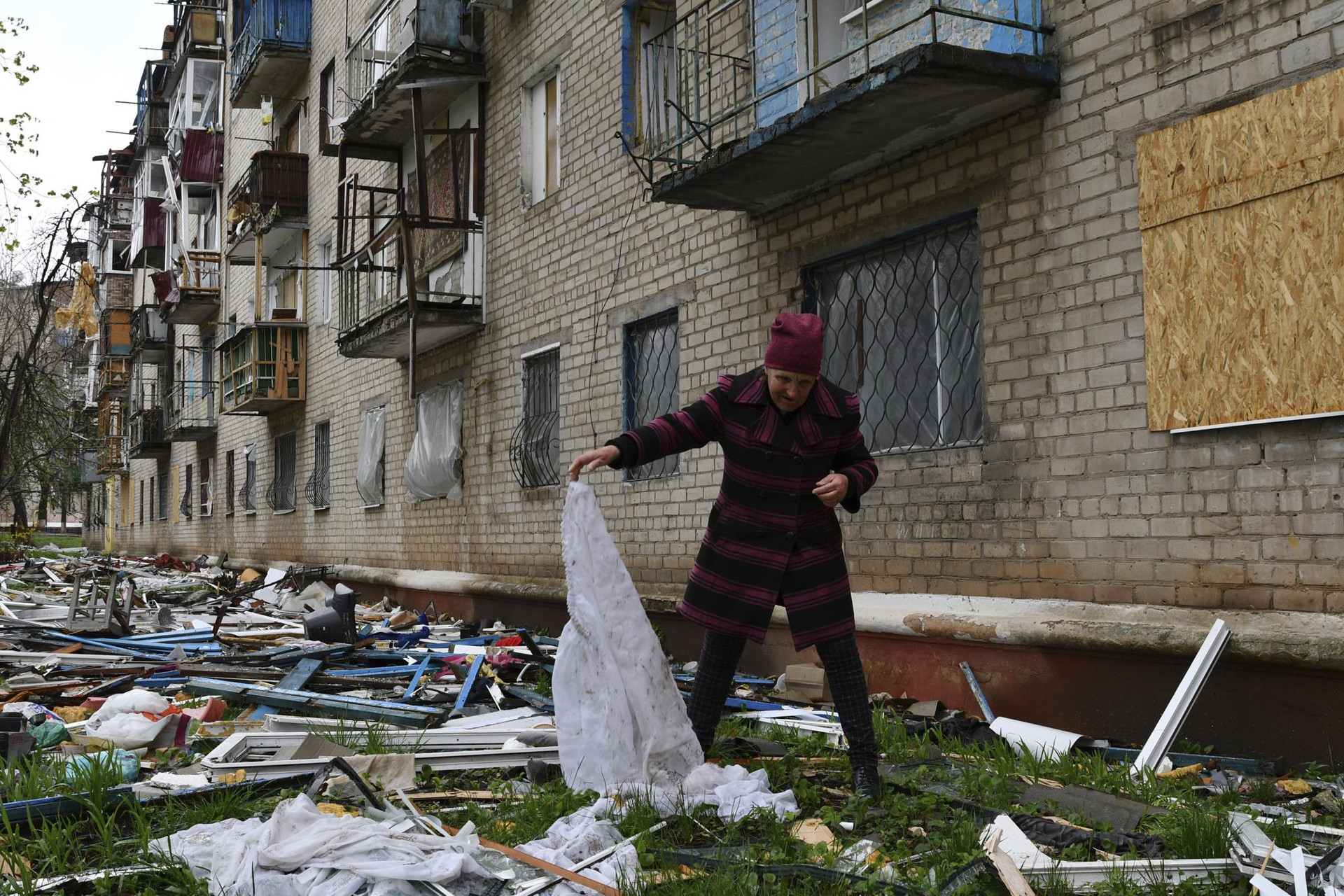 Một phụ nữ tìm kiếm đồ đạc rơi từ tòa nhà chung cư bị hư hại ở Kramatorsk, Ukraine. Ảnh: AP.