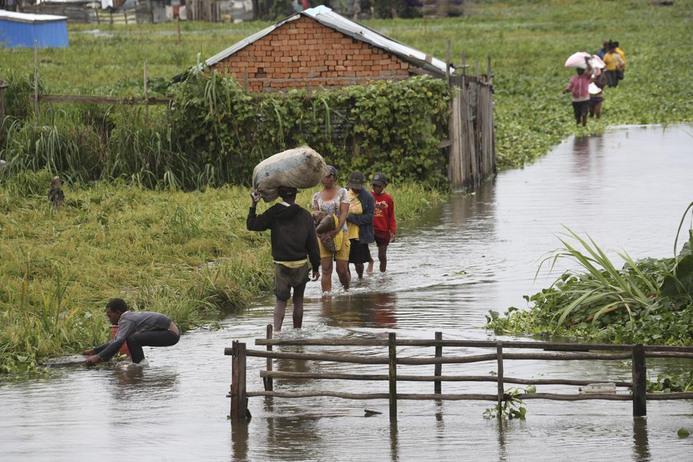 Cư dân lội qua dòng nước lũ quanh nhà sau trận mưa lớn ở Antananarivo, Madagascar (Đông Phi). Ảnh: AP.