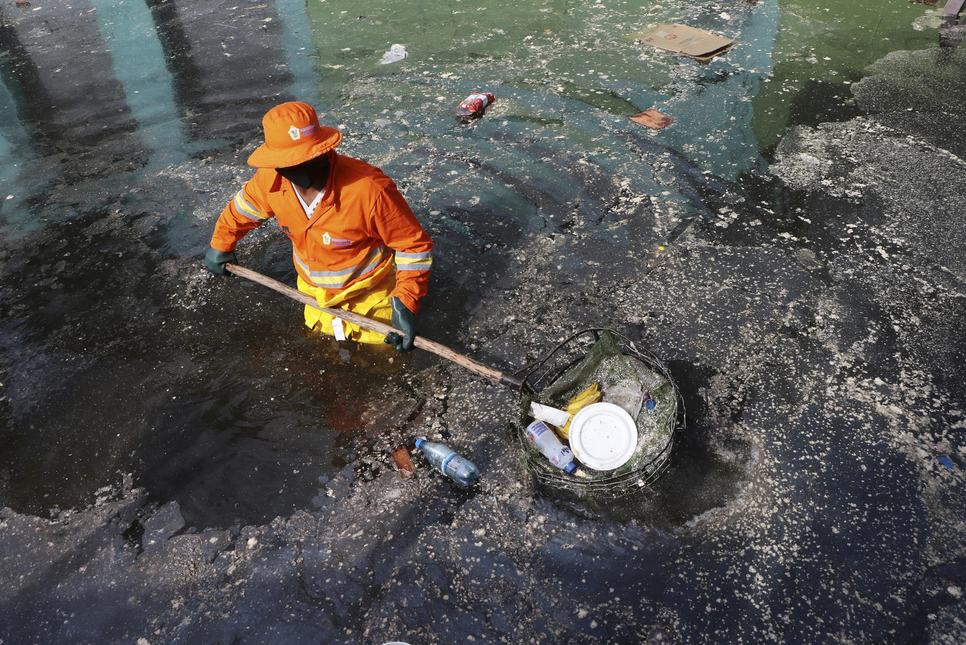 Một công nhân vớt rác trên một con phố bị ngập bởi nước sông Negro ở trung tâm thành phố Manaus, Brazil. Ảnh: AP.