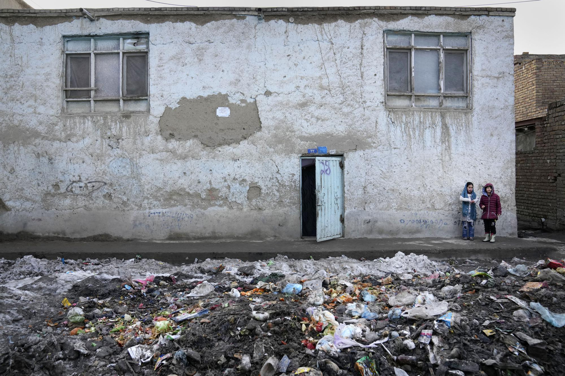 Hai đứa trẻ đứng bên ngoài ngôi nhà trên một con phố rác thải ở Kabul, Afghanistan. Ảnh: AP.