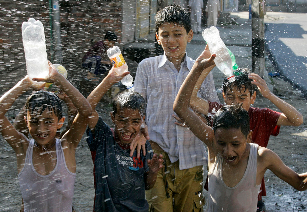 Những đứa trẻ dội nước cho trôi đi cái nóng ở Ấn Độ. Ảnh: CNN.