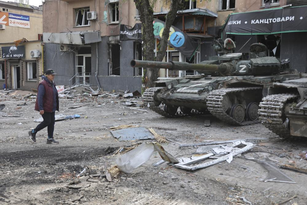 Một phụ nữ đi ngang qua chiếc xe tăng ở Mariupol, miền đông Ukraine. Ảnh: AP.