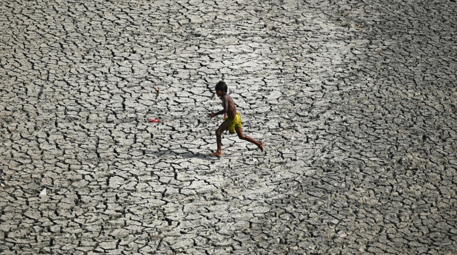 Một cậu bé chạy ngang qua vùng đáy sông khô cằn của Yamuna, con sông phụ lưu dài nhất của Ấn Độ. Ảnh: VICE.