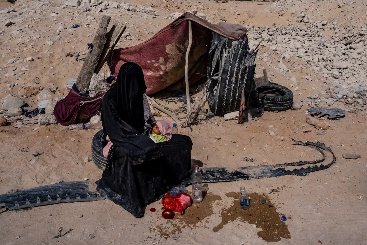Một phụ nữ và đứa con nghỉ ngơi trước một ngôi nhà tạm bợ tại con đường giữa Al Ghaydah và làng Khyseet, gần Haswayn. Ảnh: The Guardian.