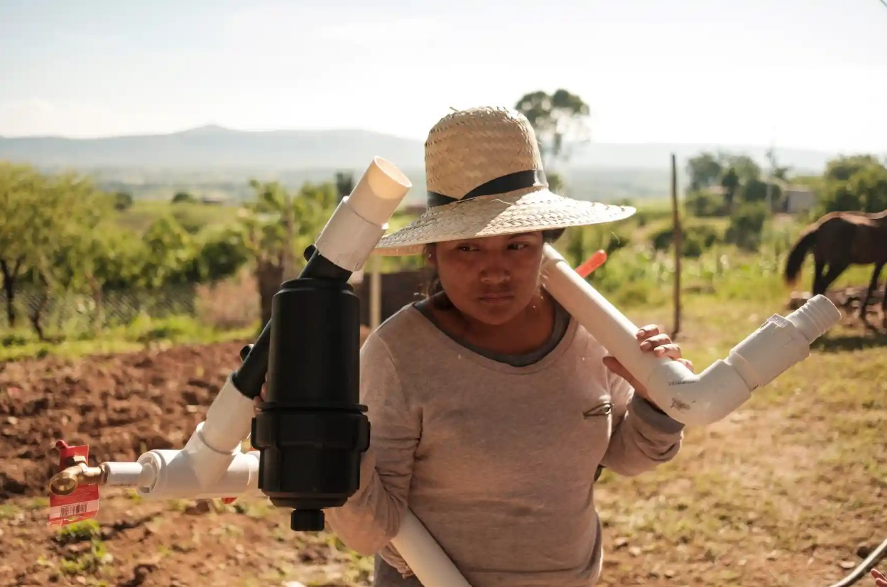 Một phụ nữ mang theo một phần của hệ thống lọc nước để giúp xây dựng một bể thu hoạch ở Mogote Colorado. Ảnh: The Guardian.