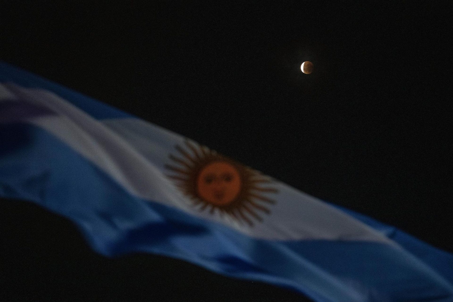 Nguyệt thực đằng sau quốc kỳ Argentina trong tuần trăng máu đầu tiên trong năm ở Buenos Aires, Argentina. Ảnh: AP.