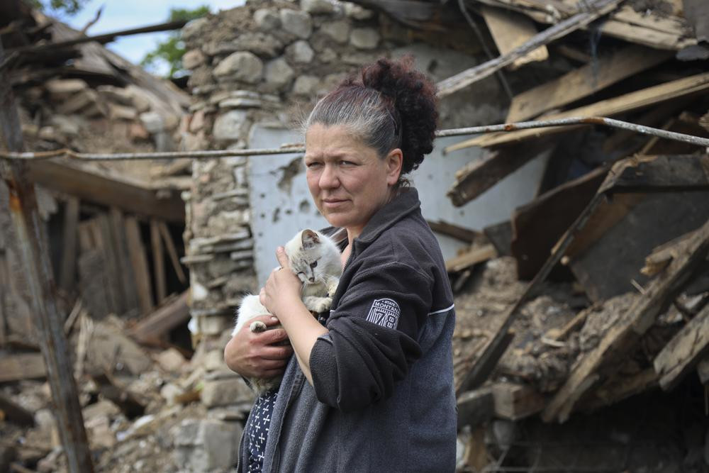 Một người phụ nữ đứng cạnh một ngôi nhà bị phá hủy ở Mariupol, miền đông Ukraine. Ảnh: AP.