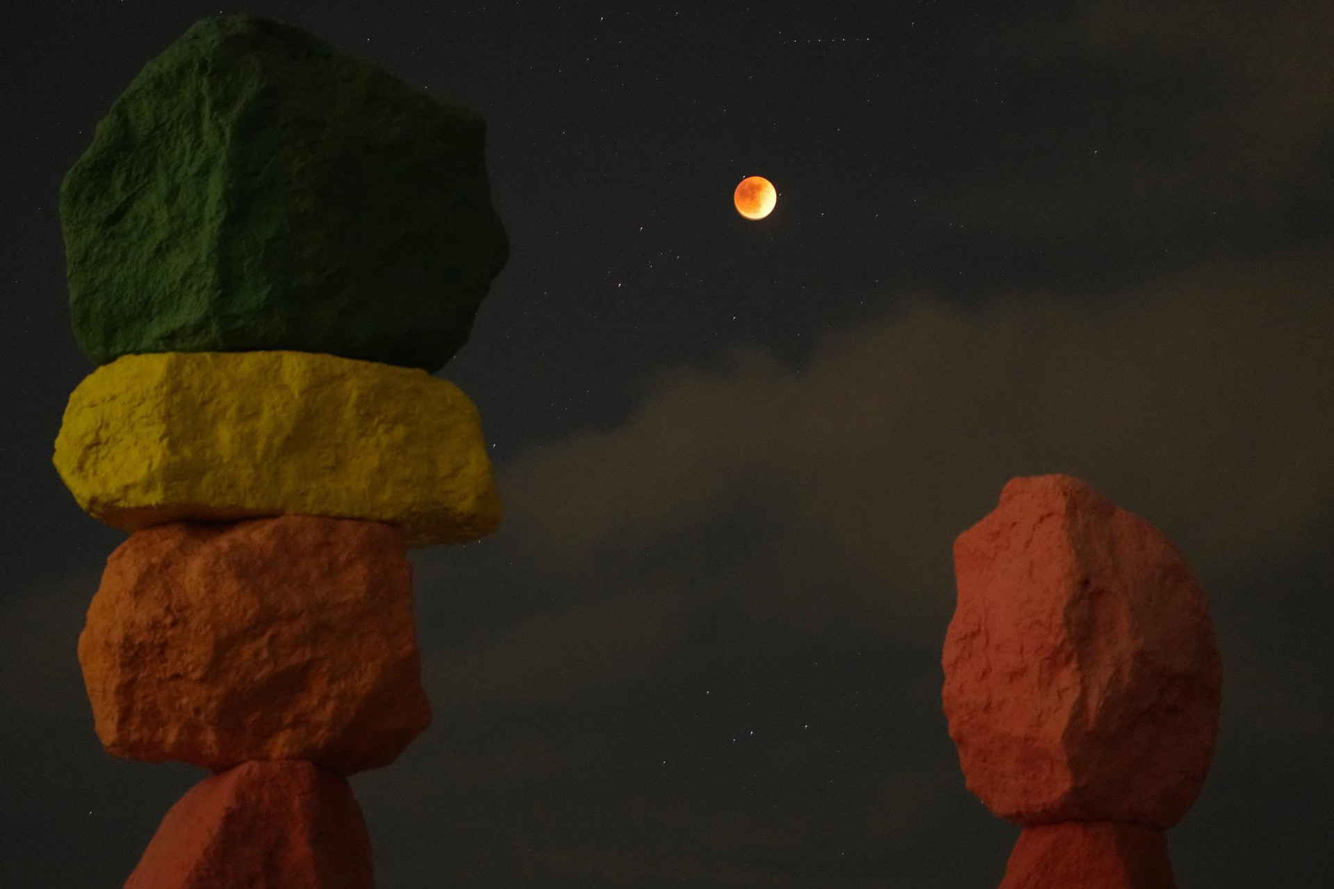 Nguyệt thực được nhìn thấy phía trên tác phẩm nghệ thuật “Bảy ngọn núi kỳ diệu” của nghệ sĩ Ugo Rondinone, sa mạc Nevada, Mỹ. Ảnh: AP.