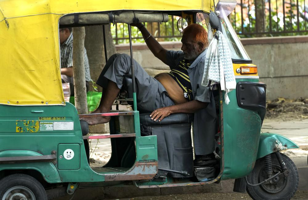 Một người lái xe kéo kiệt sức vì nắng nóng gay gắt, nằm nghỉ trong xe của mình, ở New Delhi. Ảnh: AP.