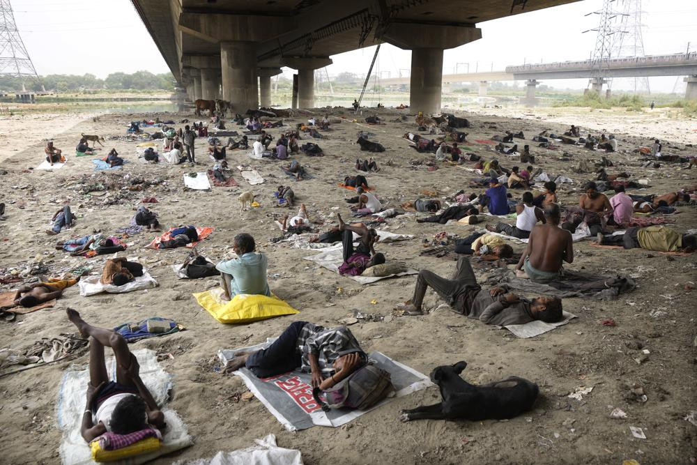 Những người vô gia cư ngủ dưới bóng mát của cây cầu vượt để tránh đợt nắng nóng ở New Delhi. Ảnh: AP.