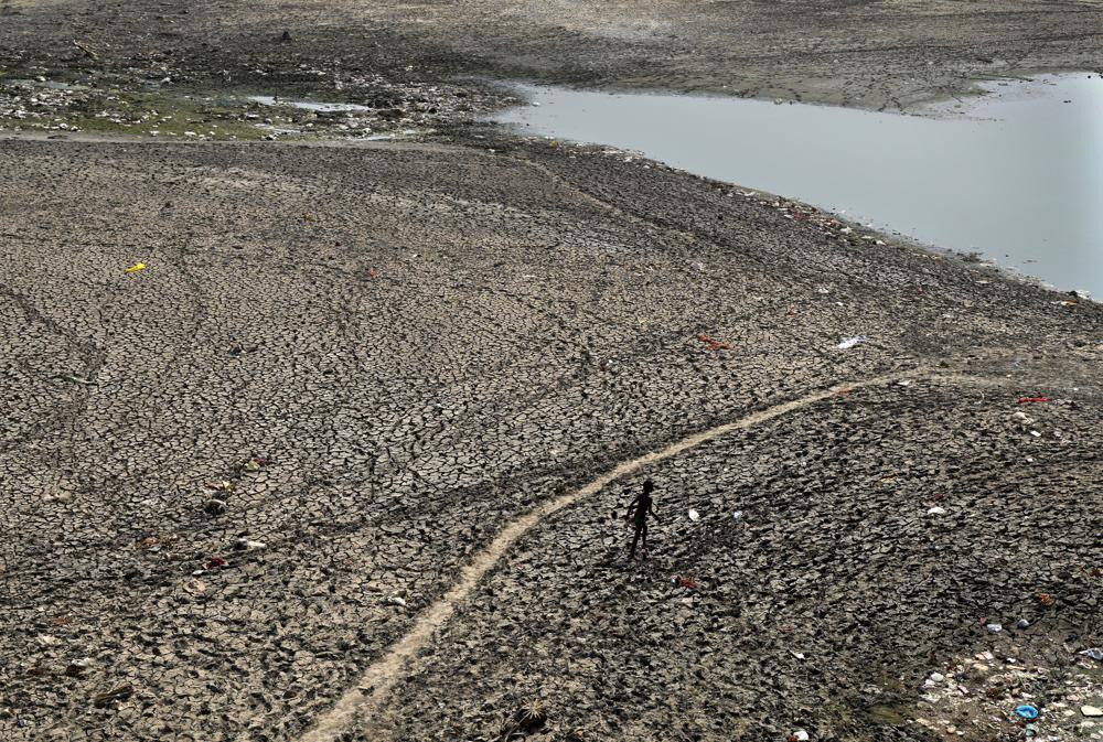 Một người đàn ông đi ngang qua khu vực khô cạn của sông Yamuna khi mực nước giảm mạnh sau đợt nắng nóng ở New Delhi. Ảnh: AP.
