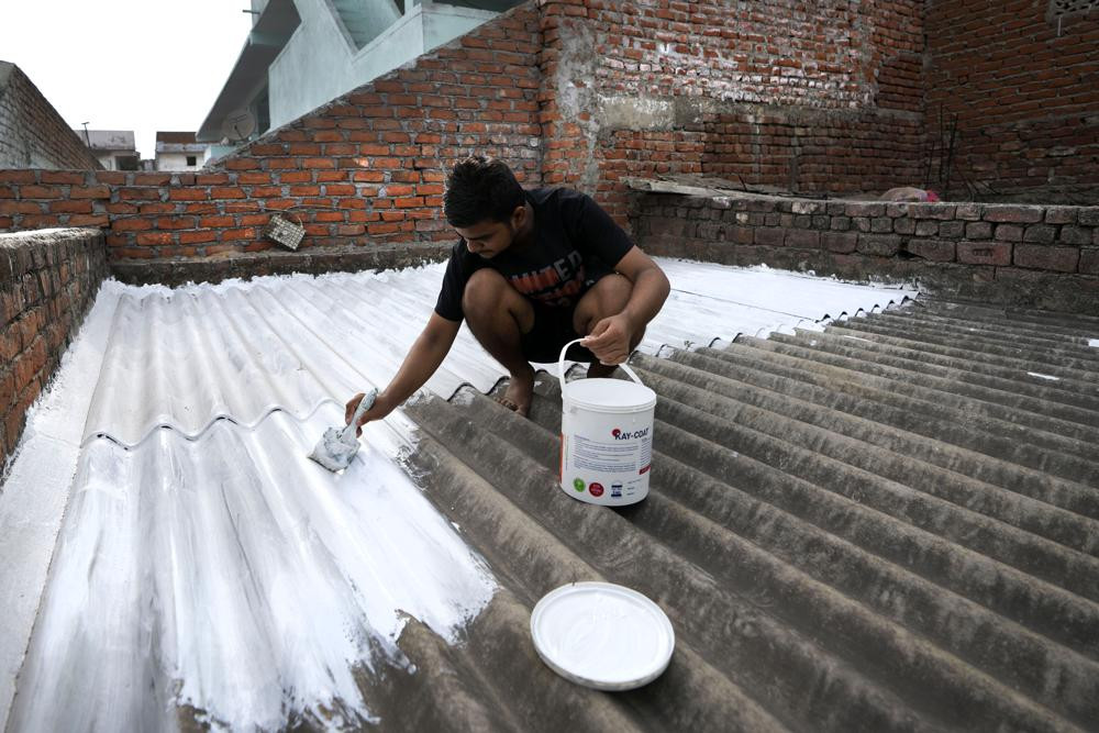 Người dân sơn mái nhà bằng sơn phản chiếu màu trắng mát mẻ, làm giảm nhiệt độ trong nhà vào mùa hè ở Ahmedabad, Ấn Độ. Ảnh: AP.