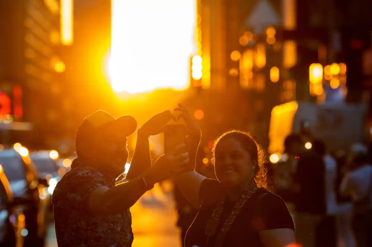 Mọi người tạo hình trái tim bằng tay trên Phố 42 khi ngắm mặt trời lặn ở Quảng trường Thời đại. Ảnh: Getty Images.