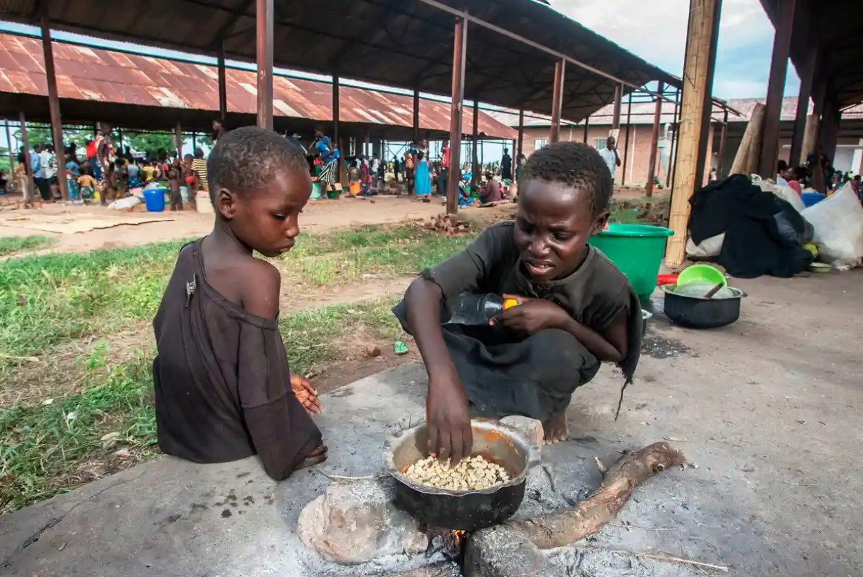 Hai đứa trẻ nấu ngô tại một trại dành cho những người phải sơ tán ở Malawi. Ảnh: The Guardian.