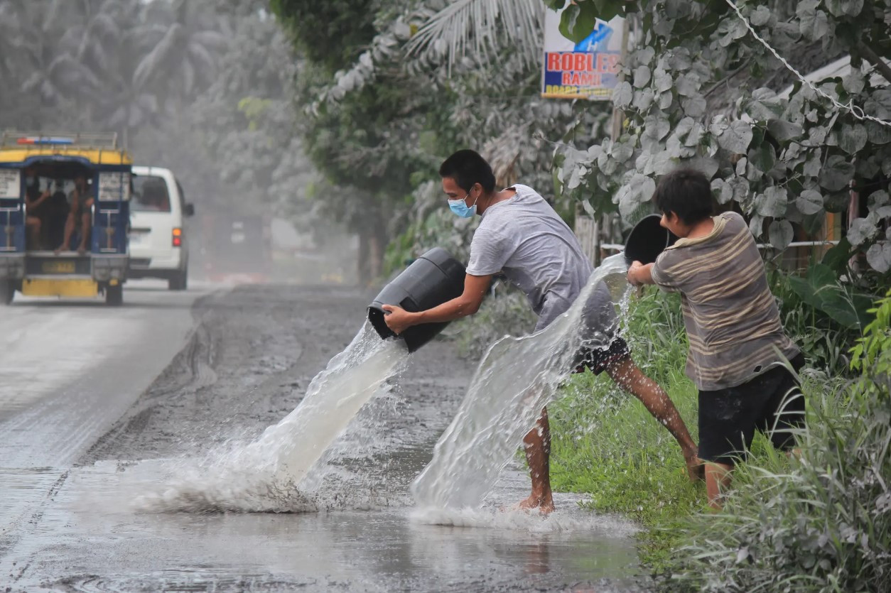 Cư dân Juban sử dụng nước để rửa tro bụi phía trước nhà của họ. Ảnh: Getty Images.