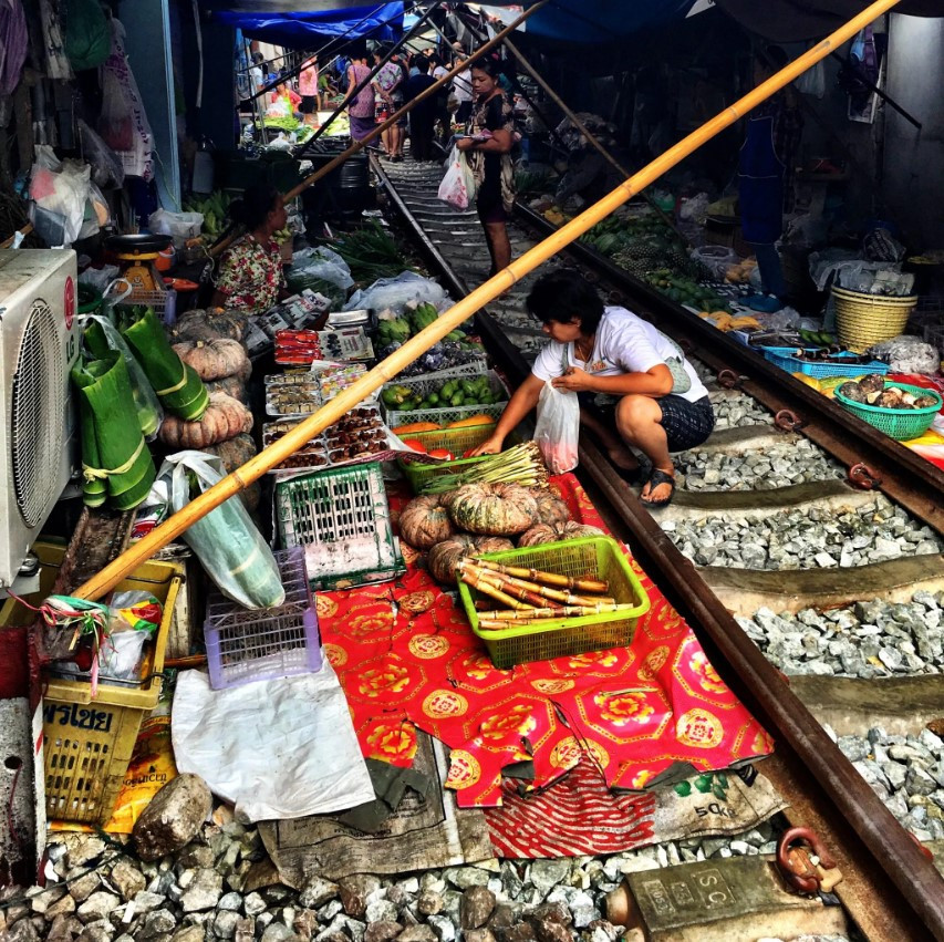 Một hành khách chọn đồ tại chợ đường sắt Mae Klong của Thái Lan. Ảnh: AFP.
