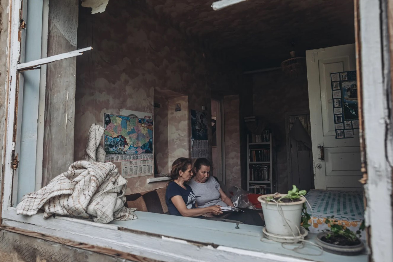 Hai người hàng xóm nghỉ ngơi trong khi giúp đỡ một người hàng xóm khác ở khu vực Donetsk. Ảnh: Getty Images.