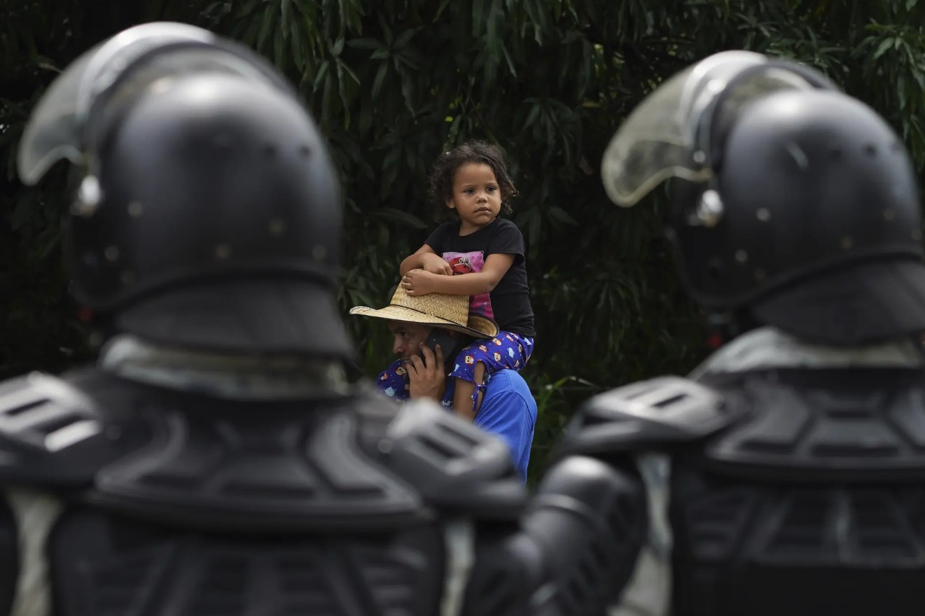 Một người đàn ông bế một đứa trẻ đi qua các thành viên của lực lượng bảo vệ quốc gia Mexico trên đường Huixtla. Ảnh: AP.