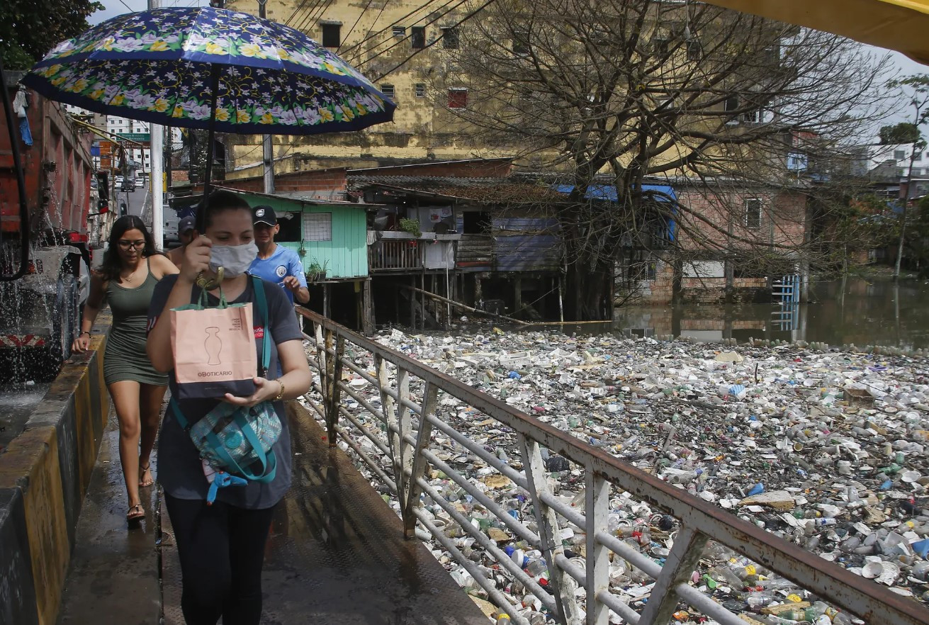 Mọi người đi qua một cây cầu rác thải tích tụ trôi nổi trên dòng sông Negro. Theo chính quyền địa phương, khoảng 35 tấn rác đang được thải ra hàng ngày khỏi nước ở Manaus. Ảnh: AP.