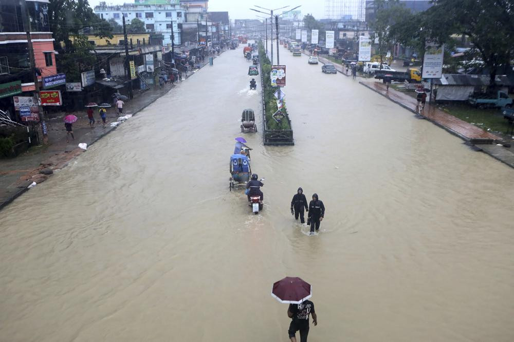 Mọi người lội qua vùng nước ngập lụt ở Sylhet, Bangladesh. Ảnh: AP.