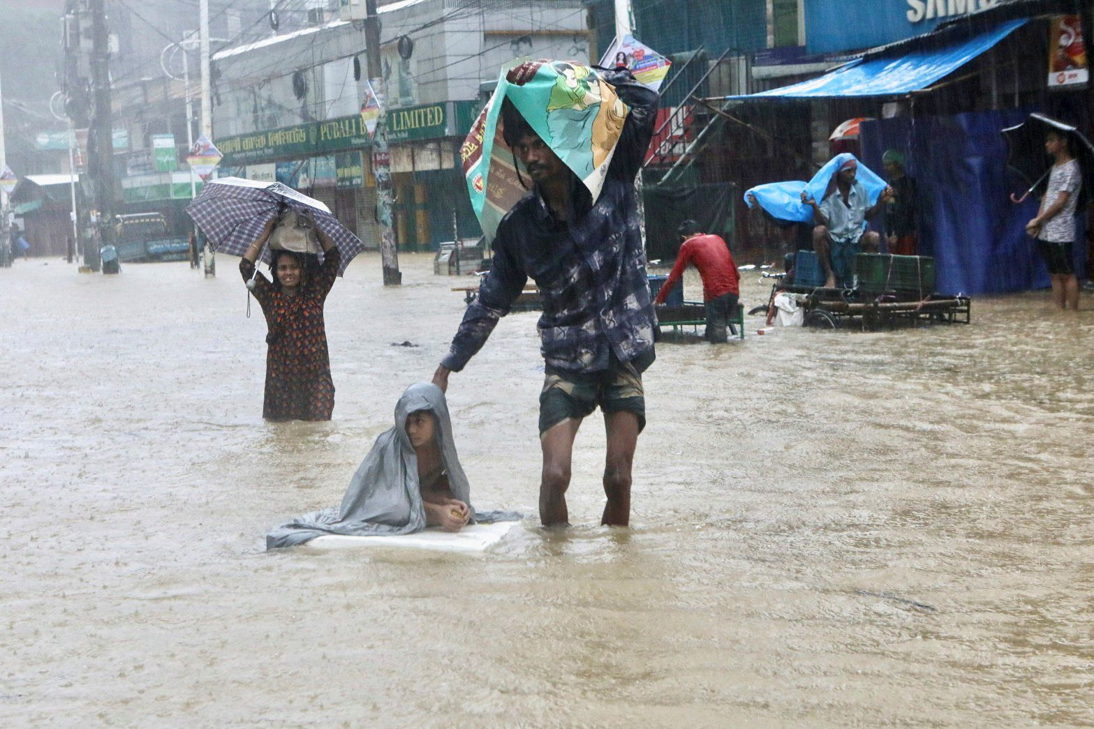 Mọi người lội qua dòng nước khi tìm nơi trú ẩn trong trận lũ lụt ở Sylhet, Bangladesh. Ảnh: Reuters.
