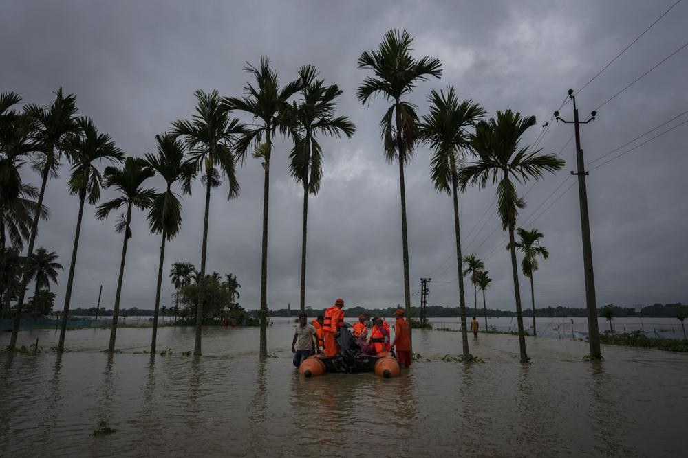 Nhân viên của Lực lượng Ứng phó Thảm họa Quốc gia (NDRF) giải cứu dân làng bị ảnh hưởng bởi lũ lụt ở làng Korora, phía tây Gauhati, Ấn Độ. Ảnh: AP.