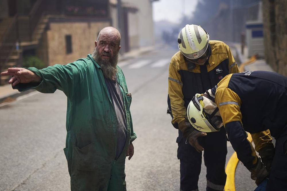 Một người hàng xóm giúp đỡ các nhân viên cứu hỏa ở San Martin de Unx, miền Bắc Tây Ban Nha. Ảnh: AP.