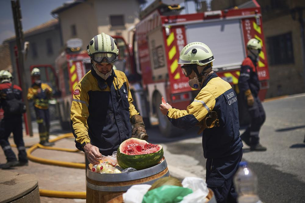 Lính cứu hỏa ăn dưa hấu trong thời gian nghỉ ngơi ở San Martin de Unx, miền Bắc Tây Ban Nha. Ảnh: AP.