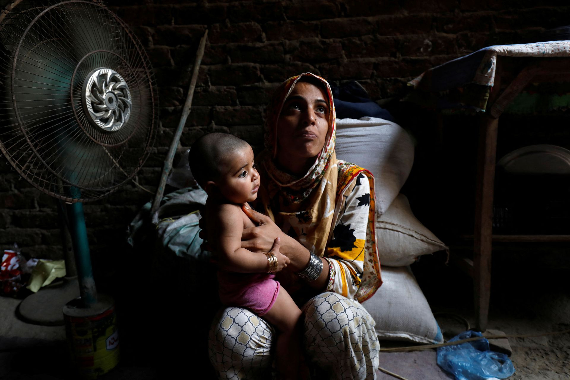 Razia 25 tuổi cùng con gái nhỏ ngồi trước quạt để giải nhiệt ở Jacobabad. Ảnh: Reuters.
