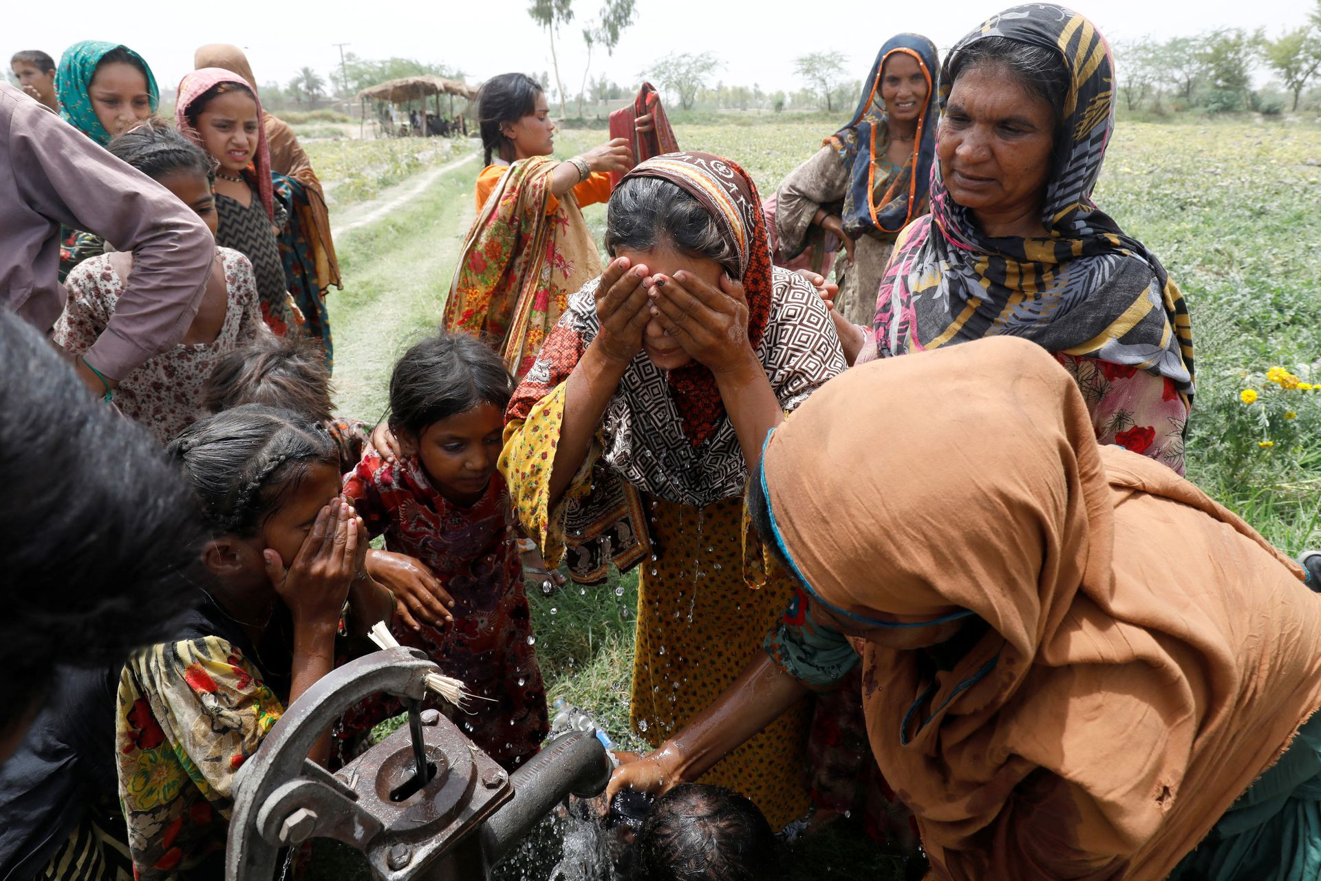 Phụ nữ và trẻ em uống nước trong một trang trại ở Jacobabad. Ảnh: Reuters.