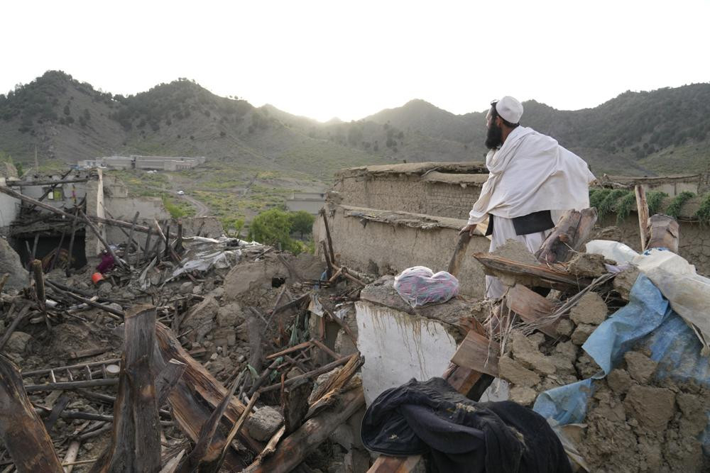 Người đàn ông đứng giữa đống đổ nát sau trận động đất ở làng Gayan. Ảnh: AP.