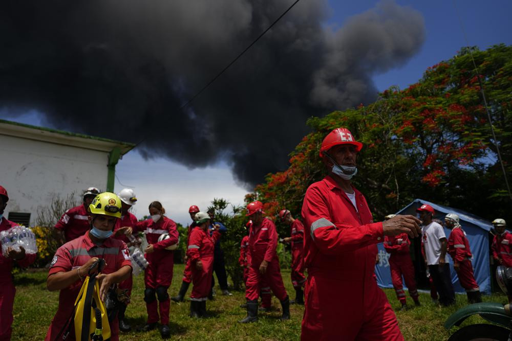 Các nhân viên cứu hỏa làm việc để dập tắt ngọn lửa bắt đầu xảy ra trong một cơn bão ở Matazanas, Cuba. Ảnh: AP.