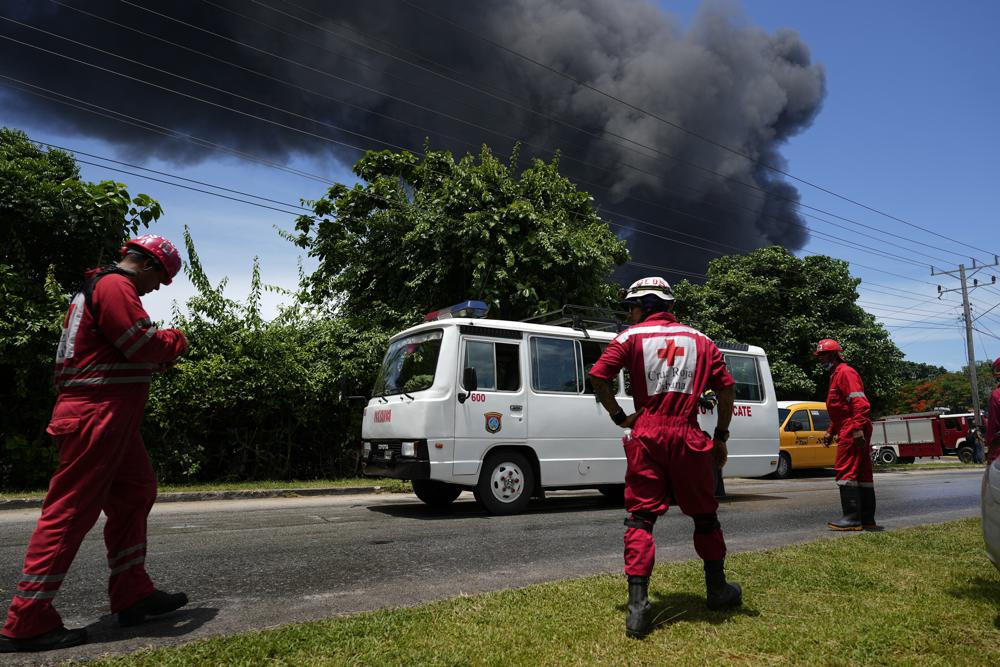 Các thành viên của Hội Chữ thập đỏ Cuba đứng chờ cứu hộ. Ảnh: AP.