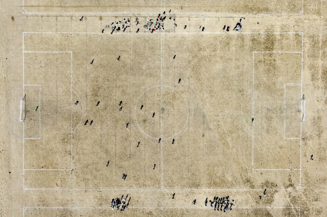 Mọi người chơi một trận bóng đá nghiệp dư của giải Vô địch Quốc gia trên sân cỏ khô trong đợt nắng nóng ở London. Ảnh: Toby Melville / Reuters.