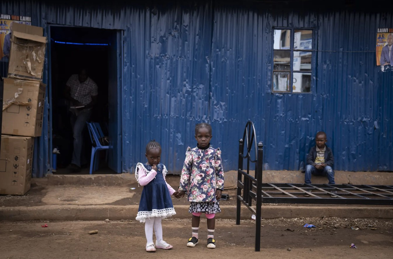 Hai bé gái nắm tay nhau sau một buổi lễ diễn ra bên trong nhà thờ Calvary ở khu phố Kibera của Nairobi. Ảnh: Ben Curtis / AP.