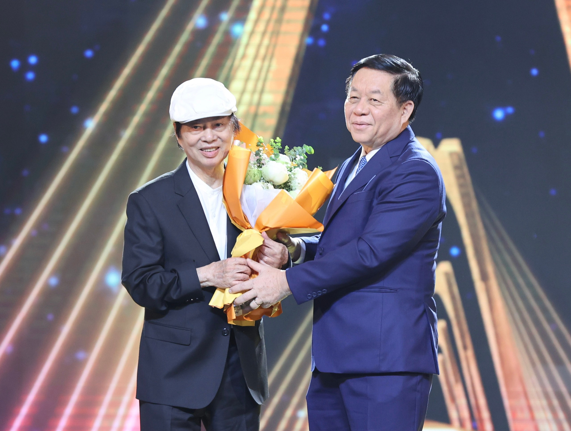 Đạo diễn Đặng Nhật Minh (trái) được ông Nguyễn Trọng Nghĩa - Bí thư Trung ương Đảng, Trưởng Ban Tuyên giáo Trung ương - tặng hoa.