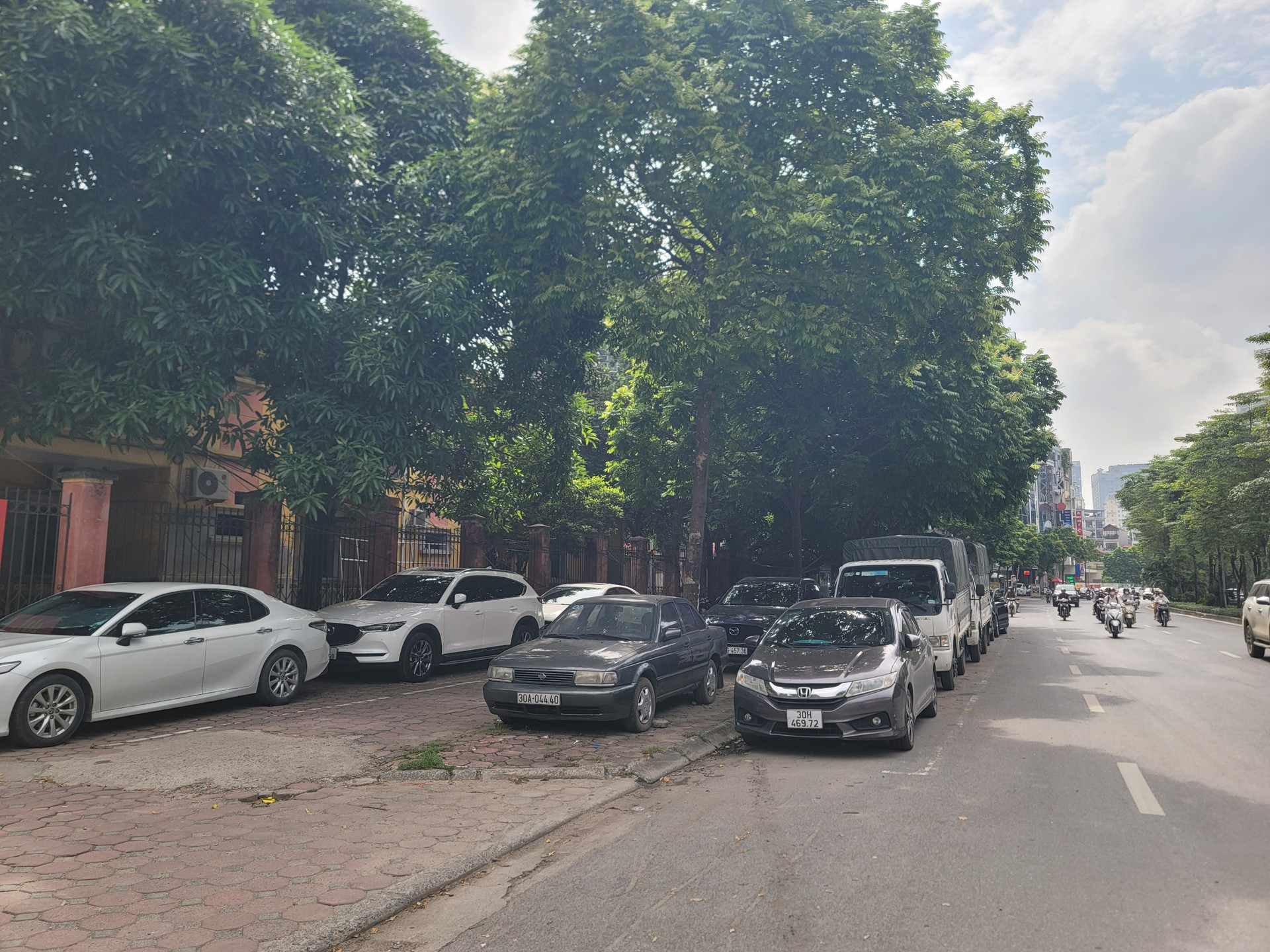Hàng loạt ô tô đậu tràn từ trên vỉa hè xuống đến lòng đường.