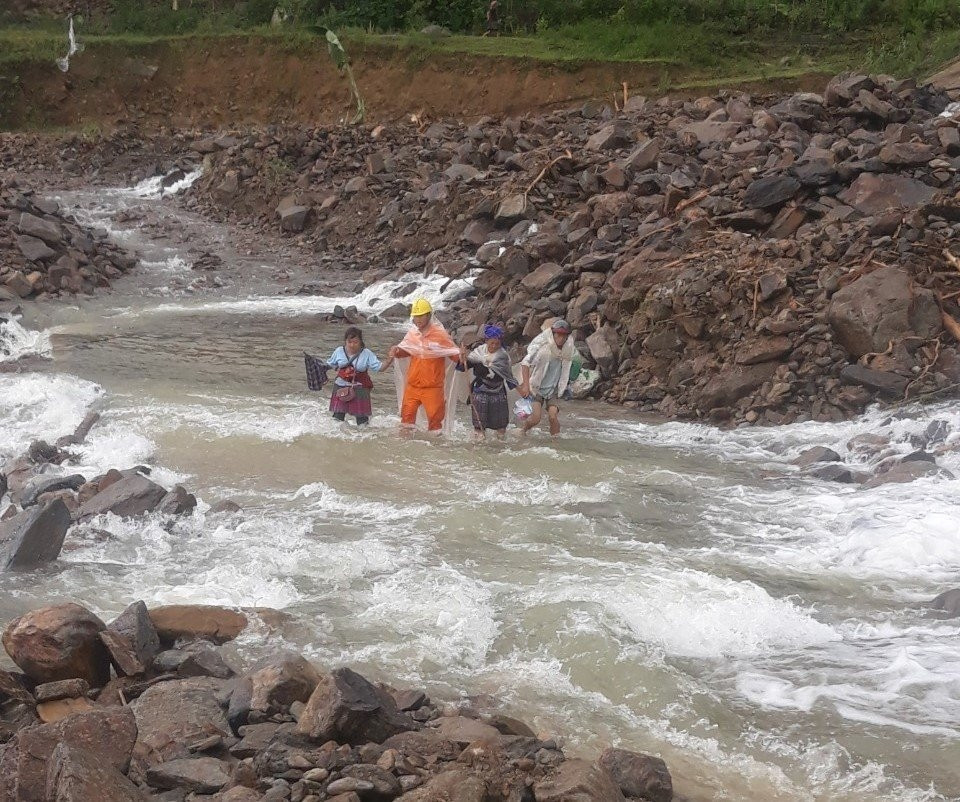 Công nhân Điện lực Than Uyên, PC Lai Châu giúp người dân qua suối.