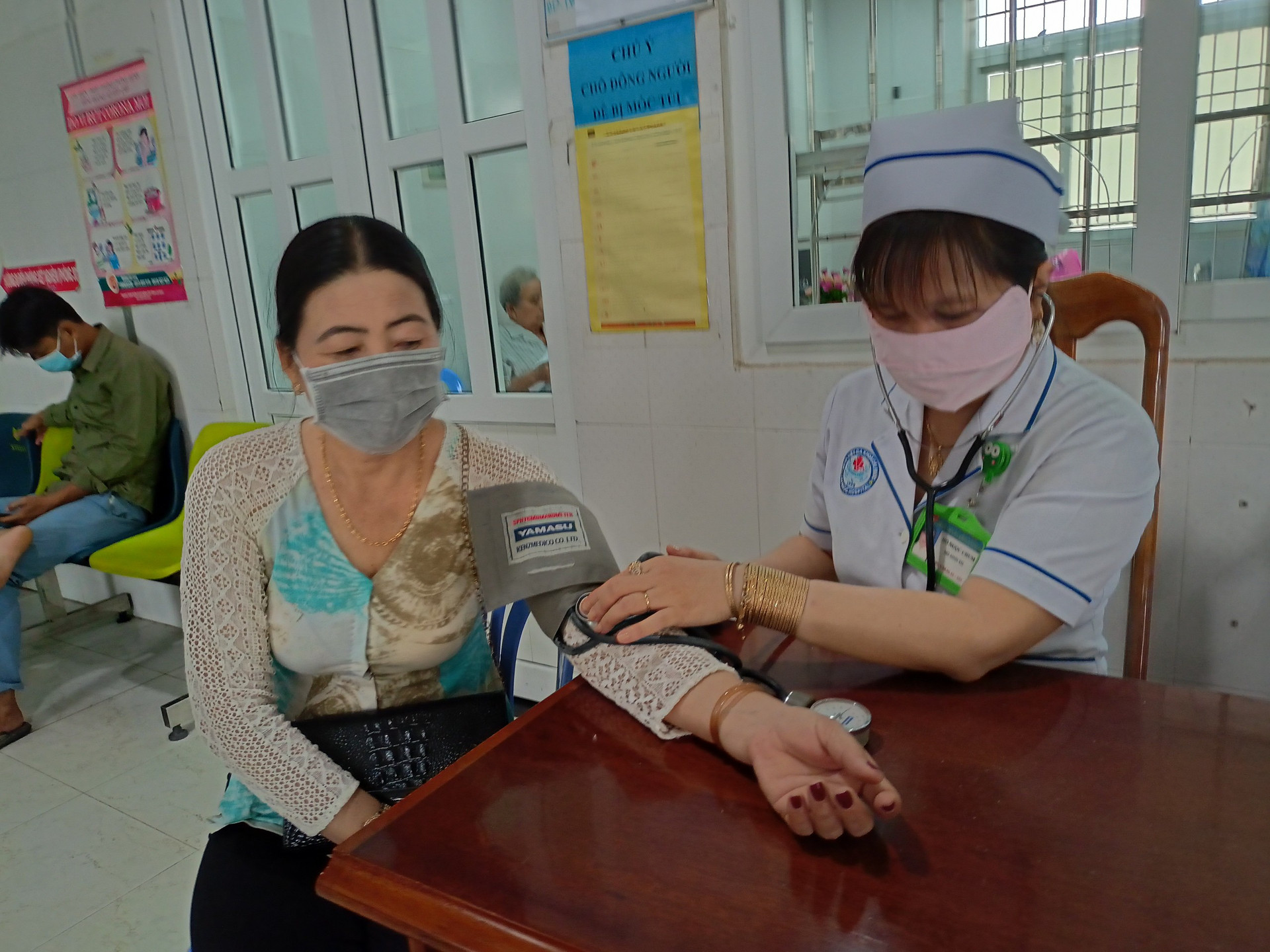 Nhân viên y tế của Bệnh viện Đa Khoa Cái Nước kiểm tra huyết áp cho bệnh nhân.