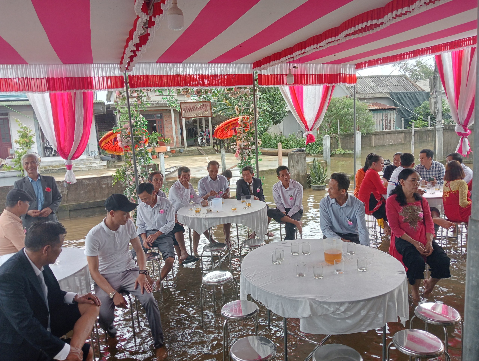 Trong quá trình tham gia, một số vị khách ngồi ở bàn được đặt tại sân nhà chú rể đang còn ngập nước.