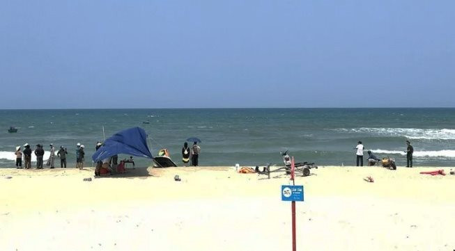 Người dân theo dõi tìm kiếm anh em sinh đôi bị sóng cuốn trôi khi tắm tại bãi biển trước Khu du lịch Resorts & Spa ở phường Hòa Hải.