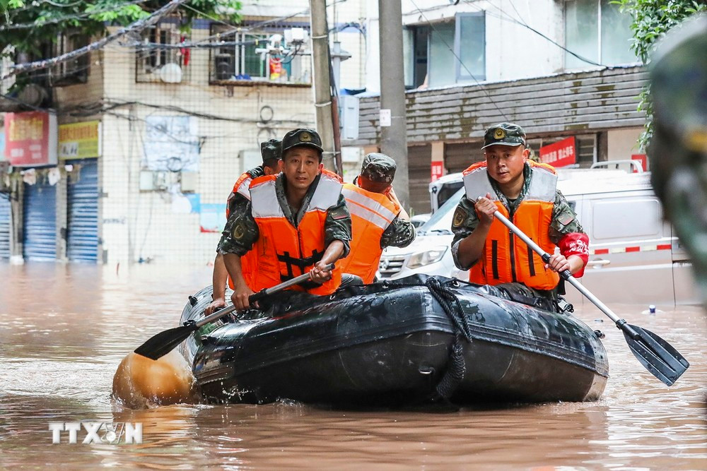 Cảnh sát Trung Quốc giúp sơ tán người dân khỏi các khu vực ngập lụt. (Ảnh: AFP/TTXVN)