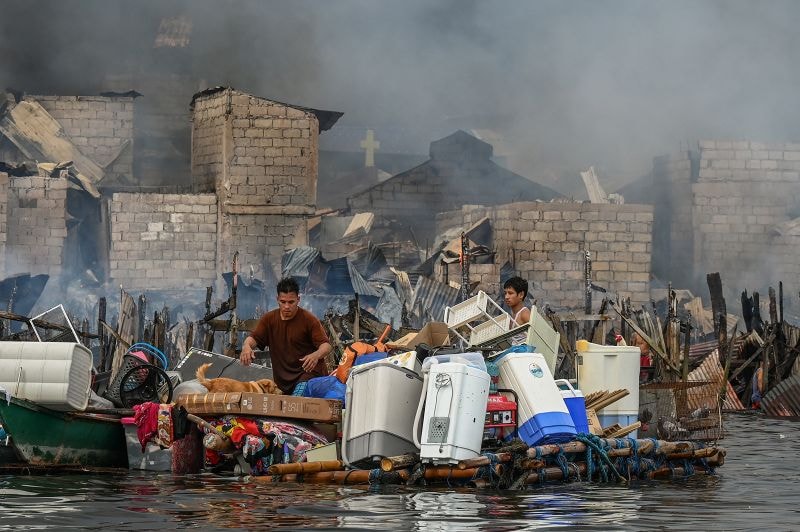 People carry their belongings on a makeshift raft during a fire in Tondo, Manila.