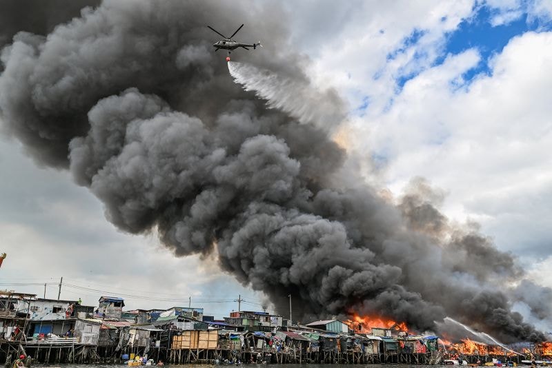 A Philippine Air Force helicopter drops water over shanty settlements ablaze in Tondo, Manila.