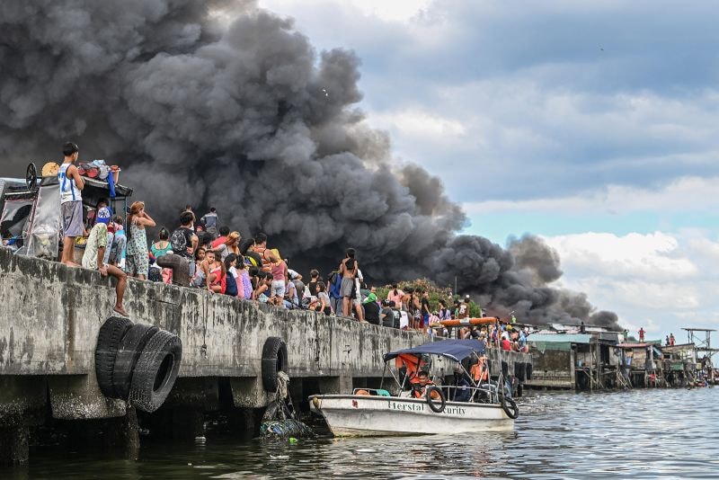 People watch houses on fire in Tondo, Manila.