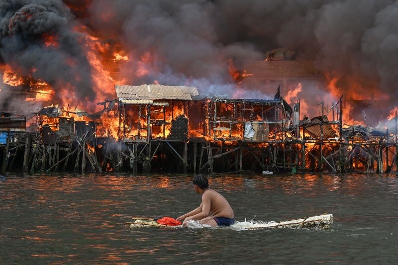 A man watches houses on fire at Tondo in Manila on November 24, 2024.